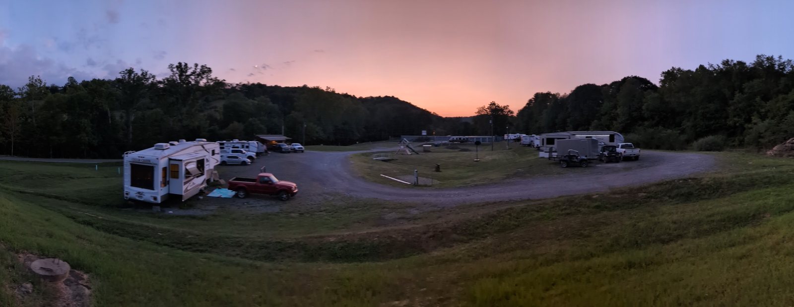 Sunset over State Line Campground, with RVs parked around the loop road and wooded hills beyond.